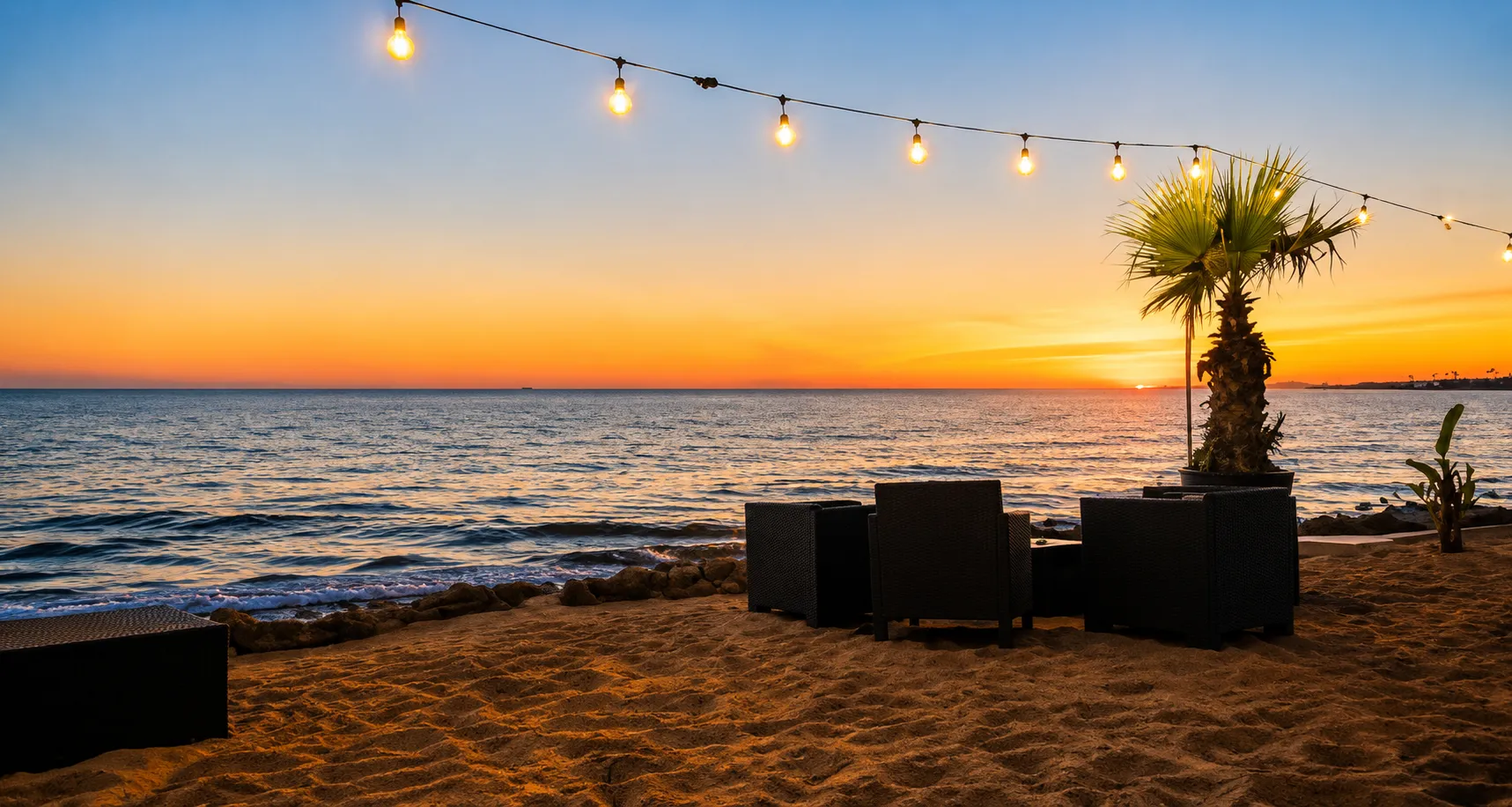 Lounge in riva al mare con luci a stringa e palma al tramonto, Golden Beach