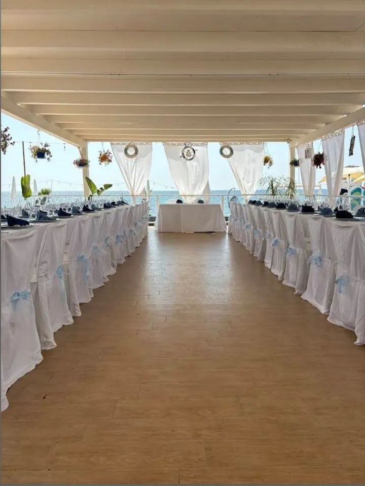 Tavolata di un evento allestita sotto la pergola del Golden Beach, vista mare